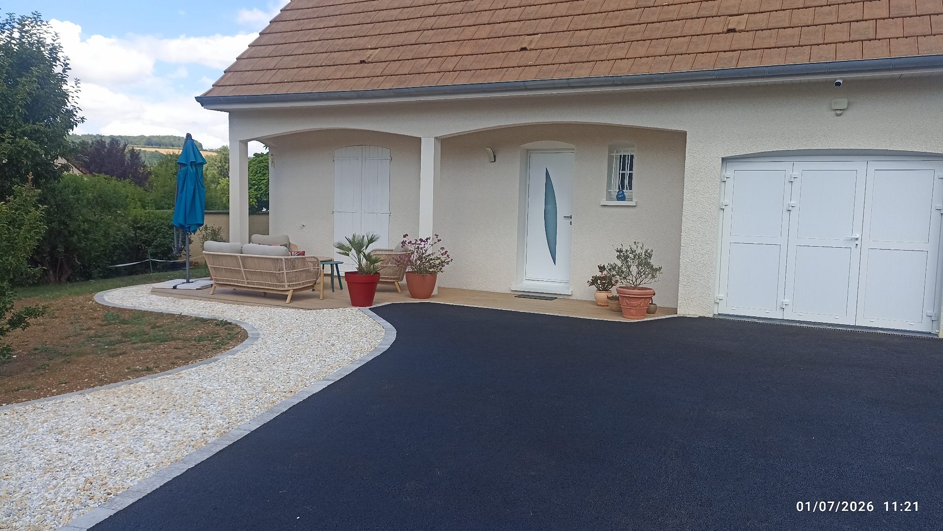 Aménagement extérieur enrobé et gravier devant maison